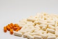 A big bunch of white pills is next to a bunch of smaller orange pills. Royalty Free Stock Photo