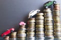 Various miniature cars on money ladder suggesting high cost for vehicles