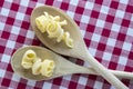 Various mix of pasta on wooden spoons on purple white checkered tablecloth, shapes ruotes and macaroni Royalty Free Stock Photo