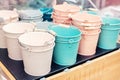 Various multicolored bright small ornamental metal buckets for sale on wooden table outdoors. Many colorful decorative mini pails Royalty Free Stock Photo
