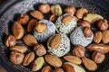 Various nuts are laid out in a brown handmade clay plate