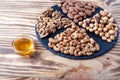 Various nuts sorted on round stone plate with honey glass bowl and honet dipper. Mixed nuts on wooden table. Black stone plate on