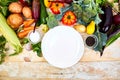 Various organic vegetables ingredients around empty plate Royalty Free Stock Photo