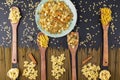 Various pastas on a green ceramic plate, bamboo spatulas and a black textured background