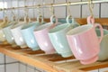 various pastelcolored ceramic mugs hanging on a kitchen rack