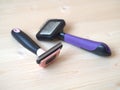 Various pet grooming tools including a slicker brush and a deshedding comb arranged on a light wooden surface Royalty Free Stock Photo