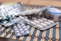 Various pills and capsules in blister packagings piled up on a glass table