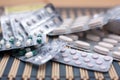 Various pills and capsules in blister packagings piled up on a glass table