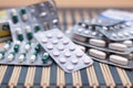 Various pills and capsules in blister packagings piled up on a glass table