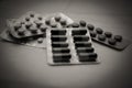 Various pills and capsules in blisters close-up, soft focus . Black and white photo with vignetting. The concept of harm from