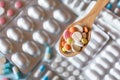 Various pills in a wooden spoon on the background of blister packs of medicines Royalty Free Stock Photo