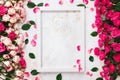 Various pink and red roses directed at each other and empty white wooden frame