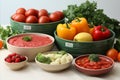 Various plates of assorted vegetables for preparing lunch laid out on kitchen table