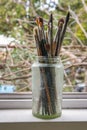 Various professional paint brushes in the transparent jar on the window sill Royalty Free Stock Photo