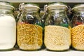 Various raw cereals, grains, beans and pasta for healthy cooking in glass jars on the kitchen shelf.Clean food, vegetarian, vegan,