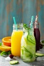 Various refreshments drinks - detox cucumber water, cherry juice and orange juice on stone table.