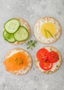 Various round healthy crackers with salmon and cheese, tomato and cucumber on light kitchen table background. Top view Royalty Free Stock Photo