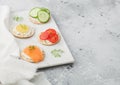 Various round healthy crackers with salmon and cheese, tomato and cucumber on marble board on light kitchen table background. Royalty Free Stock Photo