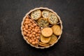 Various salty snacks in a round bowl on black table Royalty Free Stock Photo