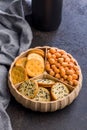 Various salty snacks in a round bowl on black table Royalty Free Stock Photo