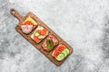 Various sandwich on a wooden board, gray grunge background. Open sandwiches with vegetables, bacon, salmon and ham