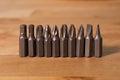 Various screwdriver heads in a horizontal row on a natural solid wood table.