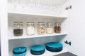 Various seeds in storage jars in pantry, white modern kitchen in background. Smart kitchen organization