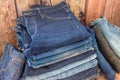 Various shades of jeans stacked on a wooden background Royalty Free Stock Photo