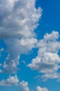 Various shape fluffy cummulus clouds accumulating on blue summer sky