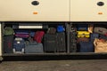 Various sizes and colors of suitcases in the cargo compartment of the bus. Close-up view of full place for luggage in the bus.