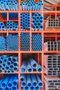 Various sizes of many blue PVC water pipes with carbon steel rectangular and square tubes on storage shelf Royalty Free Stock Photo