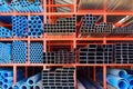 Various sizes of many carbon steel rectangular and square tubes with blue PVC water pipes on storage shelf Royalty Free Stock Photo