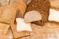 Various sliced bread on cutting board with ears, grain, flour