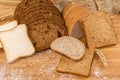 Various sliced bread on cutting board with ears, grain, flour