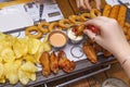 Various snacks in beer: chicken nuggets, chips, onion rings, fried chicken wings on a wooden table in a pub.