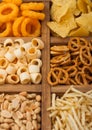 Various snacks in vintage wooden box. Onion rings,nachos, salty peanuts with potato sticks and pretzels. Suitable for beer and Royalty Free Stock Photo