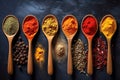 Various spices and herbs in wooden spoons on a dark table.