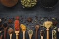 Various spices and herbs in wooden spoons and scoops. Black ceramic bowls of seasonings. Ingredients for cooking Royalty Free Stock Photo