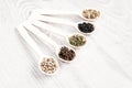 Various spices and herbs in wooden spoons on white table background. Aromatic food cooking ingredients.
