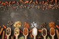 Various spices in wooden spoons on dark wooden table.