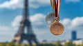 Various sports medals, gold, silver, bronze against background of Eiffel Tower under blue sky. Summer Olympics in Paris