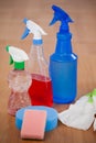 Various spray bottles, sponge and glove on wooden floor