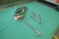 Some various surgical abdominal retractors lie side by side on a green base