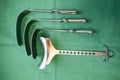 Some various surgical abdominal retractors lie side by side on a green base