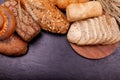 Various tasty rolls and breads with grain close up on grey background.