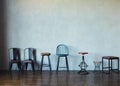 Various types of chairs and stools stand against the gray wall. Royalty Free Stock Photo