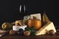 Various types of cheese with glass of wine on rustic wooden table. Dark background Royalty Free Stock Photo
