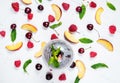 Various types of fruits with green leaves and frozen cocktail berries on white wood background Royalty Free Stock Photo