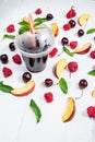 Various types of fruits with green leaves and frozen cocktail berries on white wood background Royalty Free Stock Photo