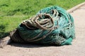 Various types of heavily used fishing nets and strong ropes with rusted chains on one large pile on edge of sidewalk next to uncut Royalty Free Stock Photo